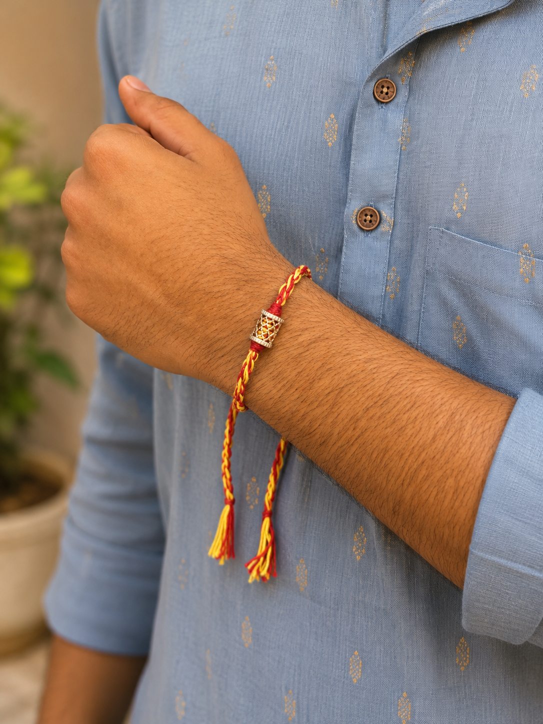 Ekta Rakhi, red and yellow braid with silver mesh bead, worn on wrist