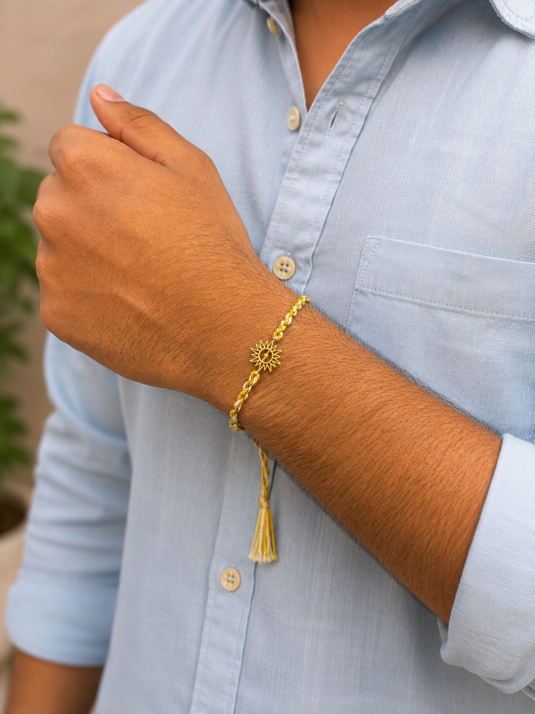 Sunshine Rakhi, yellow and white braid with sun charm, worn on wrist